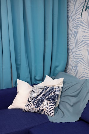 A bed with a blue bedspread, two pillows, and a blue curtain in the background.