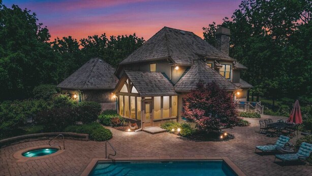 Une maison à deux étages avec une piscine, entourée d’un jardin aménagé et dotée de mobilier de jardin.