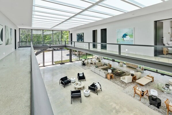 Un intérieur spacieux et moderne, doté d’un plafond haut et de grandes fenêtres, et agrémenté de différents types de mobilier et d’œuvres d’art.