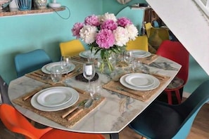 A dining table set with plates, cutlery, and a vase of flowers. - T3 Duplex Cosy with Terrace and Sea View - 5 min from the Beach (Marseille)