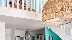 Una cocina moderna con un refrigerador de acero inoxidable, una lámpara colgante de mimbre y una pared de acento color aguamarina.