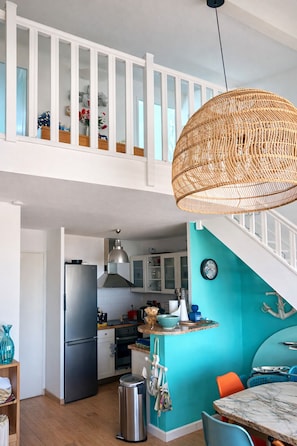 A modern kitchen with a stainless steel refrigerator, a hanging wicker light fixture, and a teal accent wall. - T3 Duplex Cosy with Terrace and Sea View - 5 min from the Beach (Marseille)