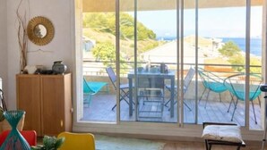 Una habitación con un gran ventanal corredero que da a una terraza exterior con mesa y sillas.