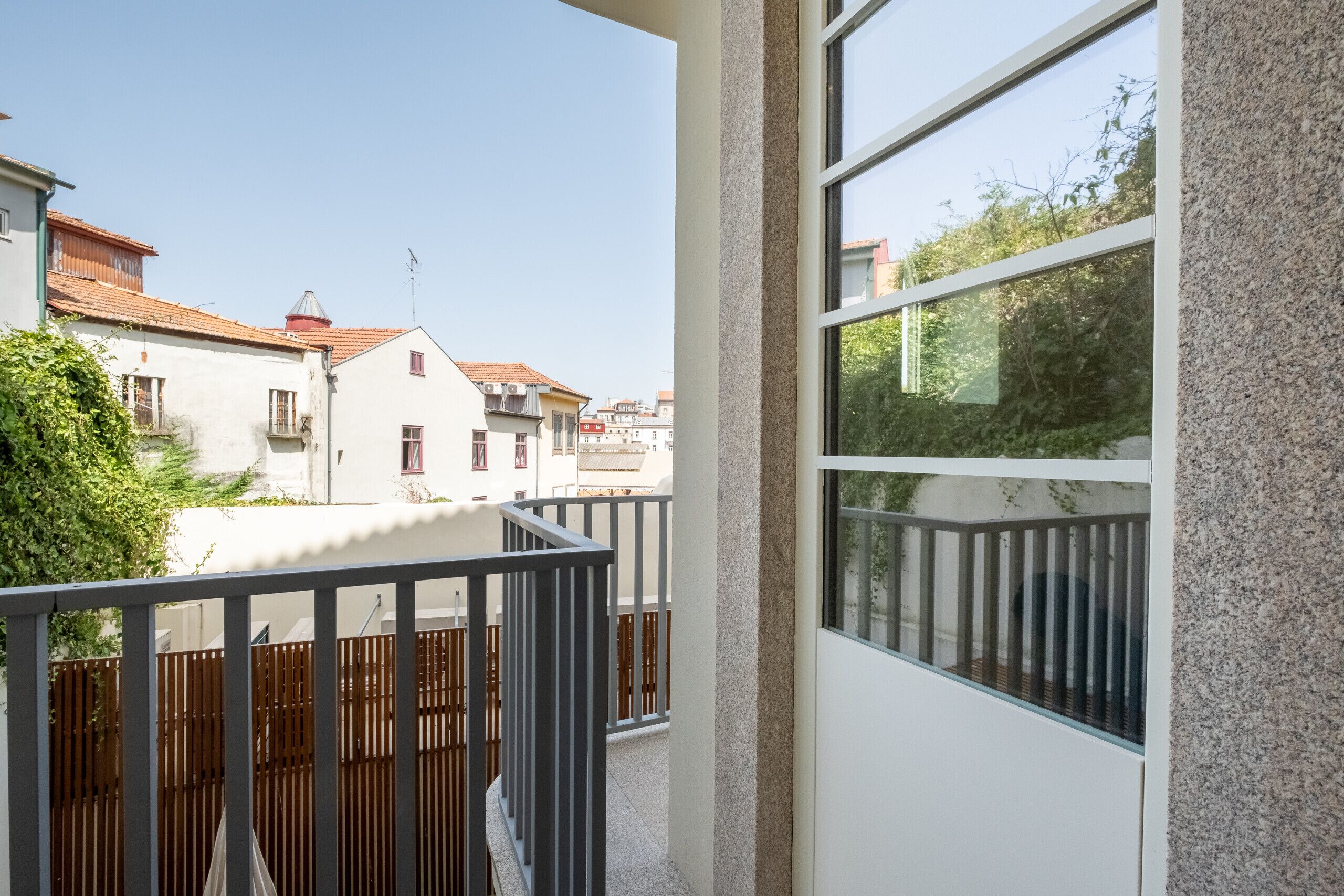 A balcony with a view of neighboring buildings and a wooden fence.