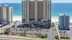 A multi-story hotel with a parking lot and a view of the beach. - Newly Updated Gulf Front 2-Bedroom Condo; Direct Ocean Views in Gulf Shores, AL (Gulf Shores)