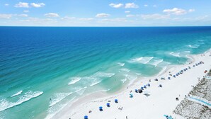 A beach with clear blue water, white sand, and blue umbrellas. - Newly Updated Gulf Front 2-Bedroom Condo; Direct Ocean Views in Gulf Shores, AL (Gulf Shores)