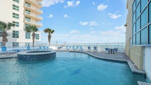 A pool area with lounge chairs, a circular hot tub, and a view of the ocean. - Newly Updated Gulf Front 2-Bedroom Condo; Direct Ocean Views in Gulf Shores, AL (Gulf Shores)