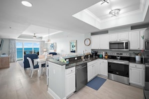 Una cocina moderna con armarios blancos, electrodomésticos de acero inoxidable y un comedor con vistas.