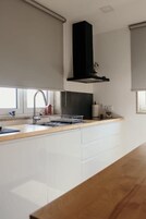 Una cocina moderna con encimera de madera, armarios blancos, una campana extractora negra y una ventana con vistas.