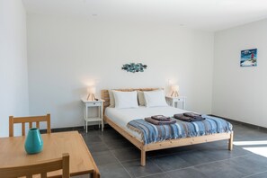 Une chambre à coucher avec un lit en bois, deux tables de chevet avec des lampes, une chaise et une petite table sur laquelle est posé un vase.