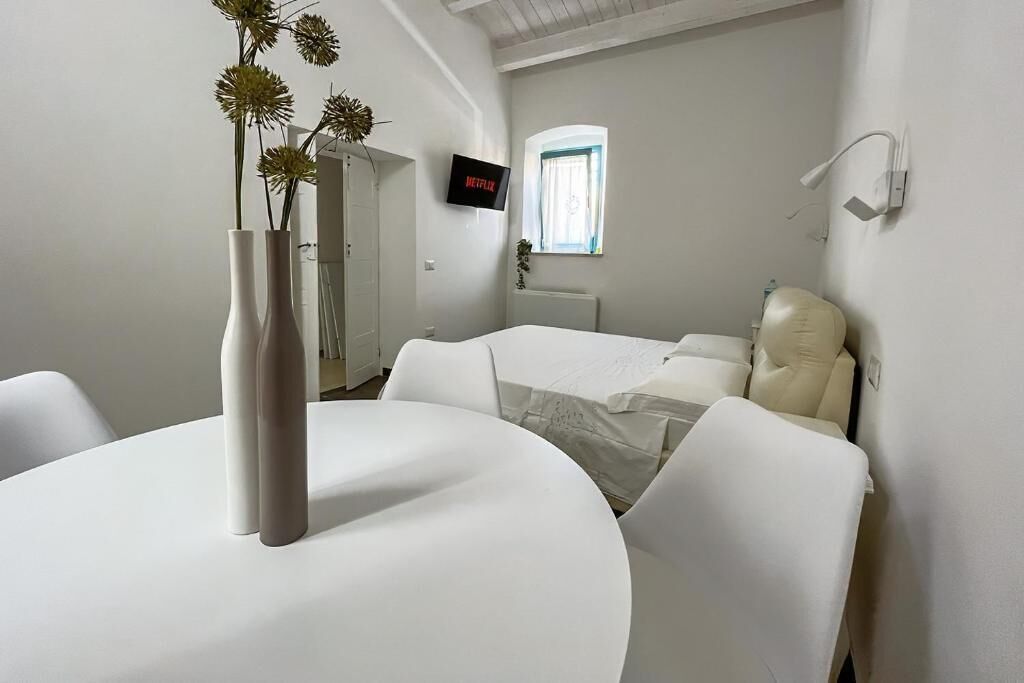 A modern bedroom with a bed, bedside tables, a TV, and a window.