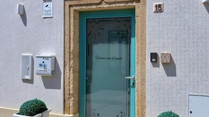 A building with a turquoise door labeled "Dimora Città," a small green bush, and a number "15" on the wall. - B&B Dimora Orrù (Cabras)