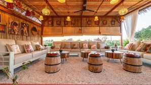 A cozy lounge area with a sofa set, round wooden stools, and a decorative ceiling. - Geeta Bagh - Luxury Private Pool Villa In Pushkar (Riyanbaddi)