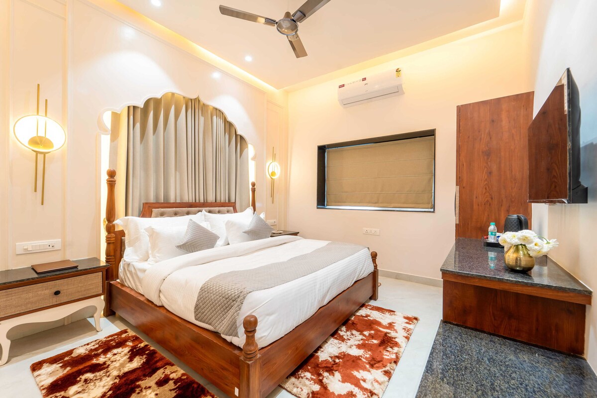 A bedroom with a wooden bed, a desk, a ceiling fan, and a mounted TV.