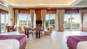 A spacious room with two beds, a TV, a dining table, and a balcony with a view of the mountains. - Geeta Bagh - Luxury Private Pool Villa In Pushkar (Riyanbaddi)