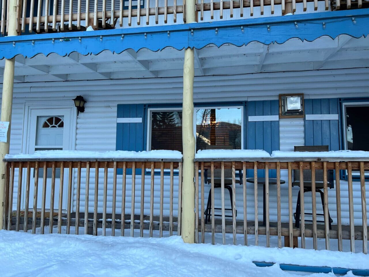 A wooden building with a blue porch and a white exterior.