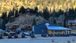 Un edificio con un letrero que dice 'Wilderness Lodge', rodeado de vehículos estacionados y un paisaje montañoso.