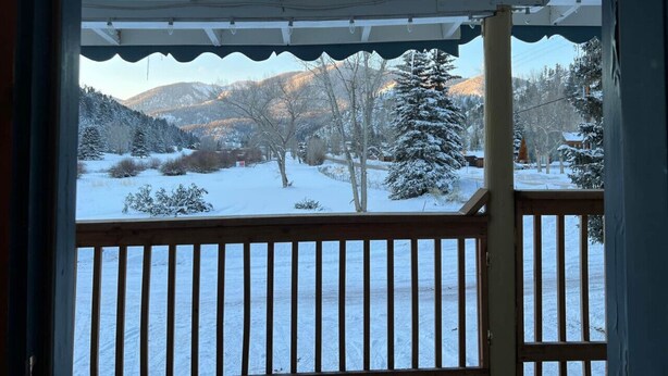 A wooden balcony with a view of a snowy landscape and mountains. - Room 9 at Bellamy's Haus (Red River)