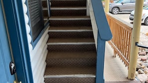 A staircase leading to a porch with a railing, a door with a window, and a car parked outside. - Room 10 at Bellamy's (Red River)