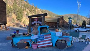 A vintage blue truck with a sign reading "Braves Old Town" parked in a parking lot with mountains in the background. - Room 5 at Bellamy's Haus (Red River)