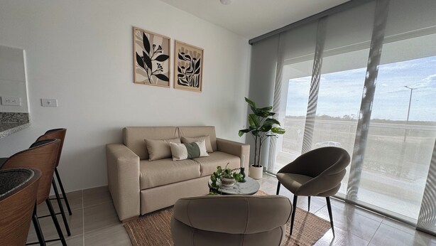 Un salon moderne comprenant un canapé, un fauteuil, une table basse et deux œuvres d’art accrochées au mur.