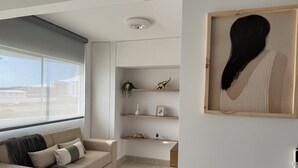 Un salon moderne avec un canapé, une étagère murale agrémentée d’objets décoratifs et une œuvre d’art encadrée.