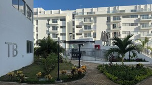 Un bâtiment moderne, orné d’une enseigne « TB », entouré d’un jardin bien entretenu, agrémenté de palmiers et d’arbustes.