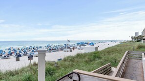 Une plage avec des parasols, des chaises longues et un panneau indiquant la présence d’un sauveteur.