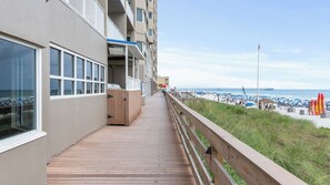 Une terrasse en bois qui mène à une plage, avec une jetée en arrière-plan.