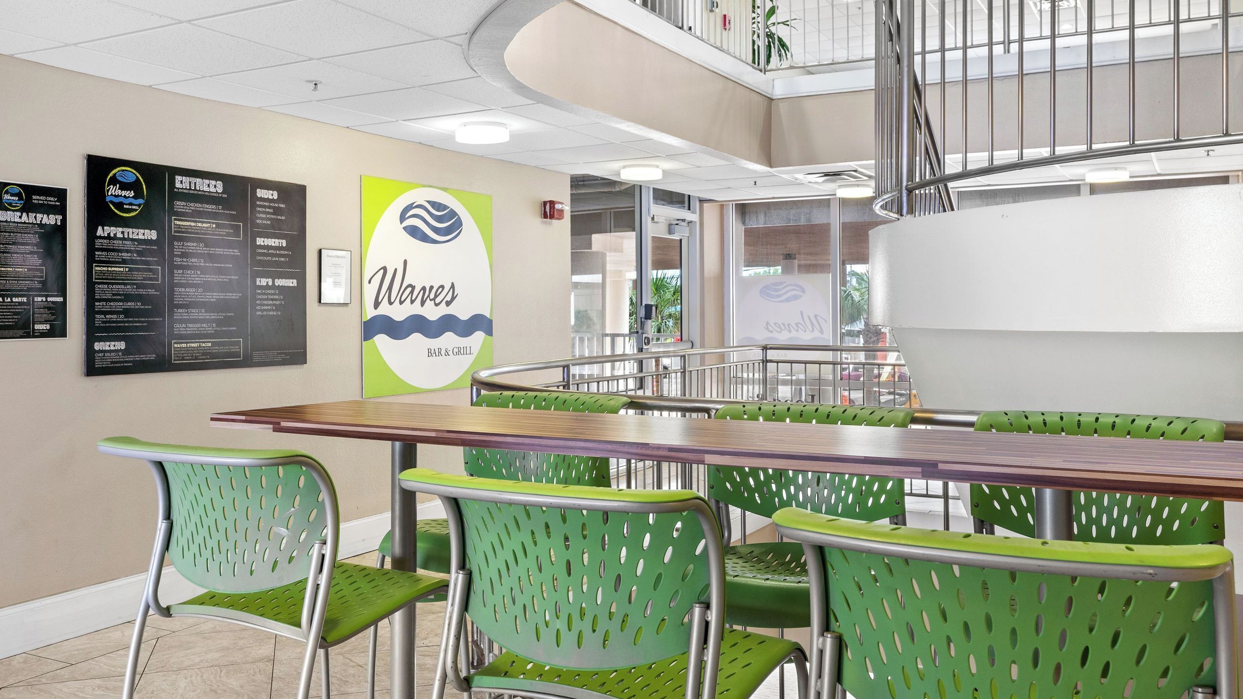 Un restaurante con una pizarra de menú, sillas verdes y una mesa de madera.