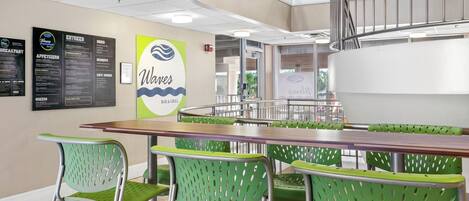 Un restaurante con una pizarra de menú, sillas verdes y una mesa de madera.