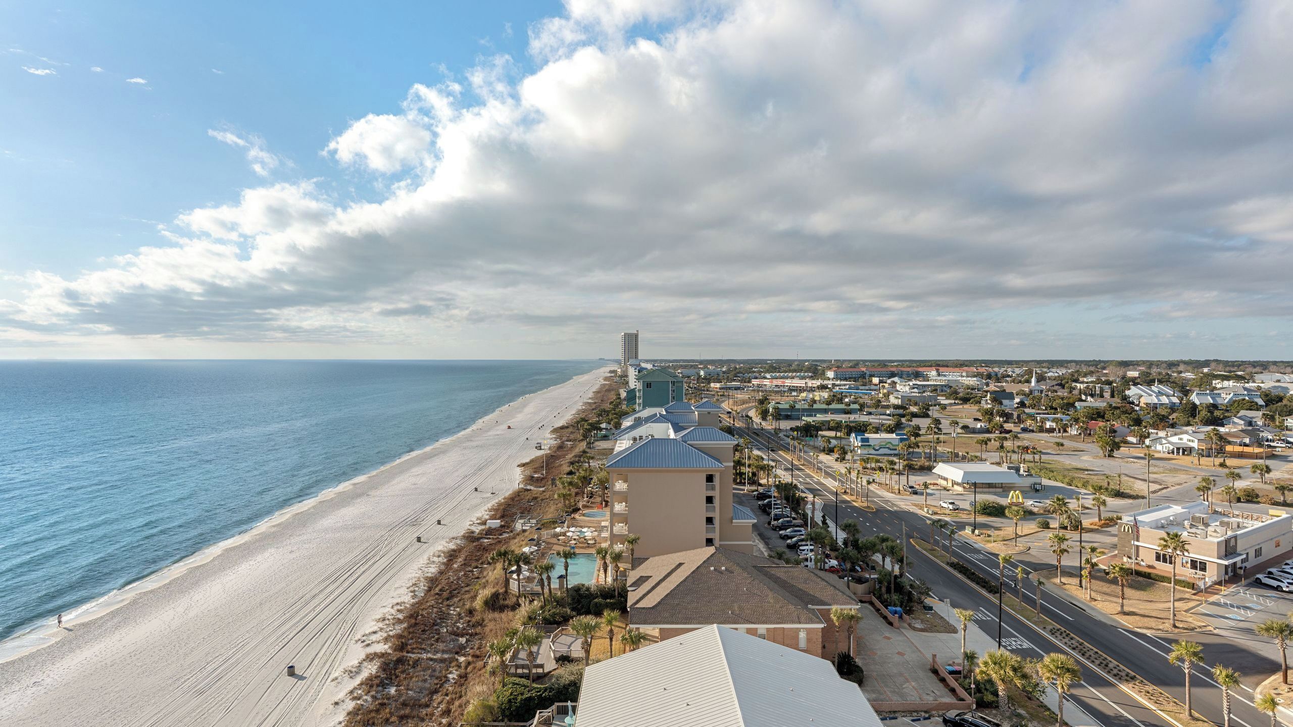 A coastal hotel with a beach view, multiple buildings, and a clear sky.