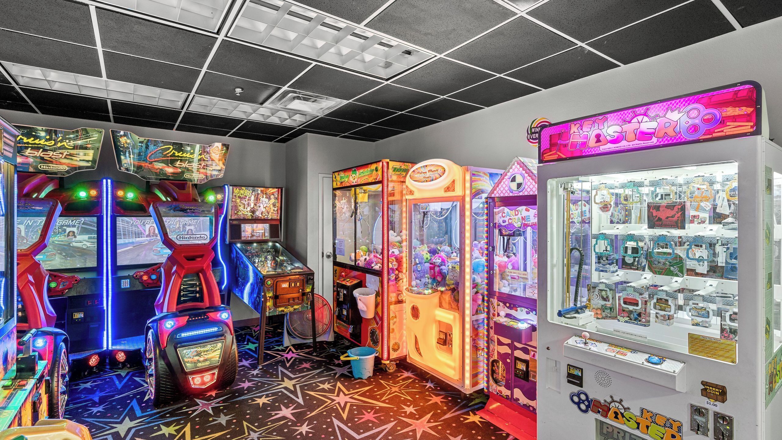 A gaming arcade with various machines, including claw games and racing games.