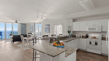 Una cocina moderna con encimeras de granito, muebles blancos y una isla central con fruta.