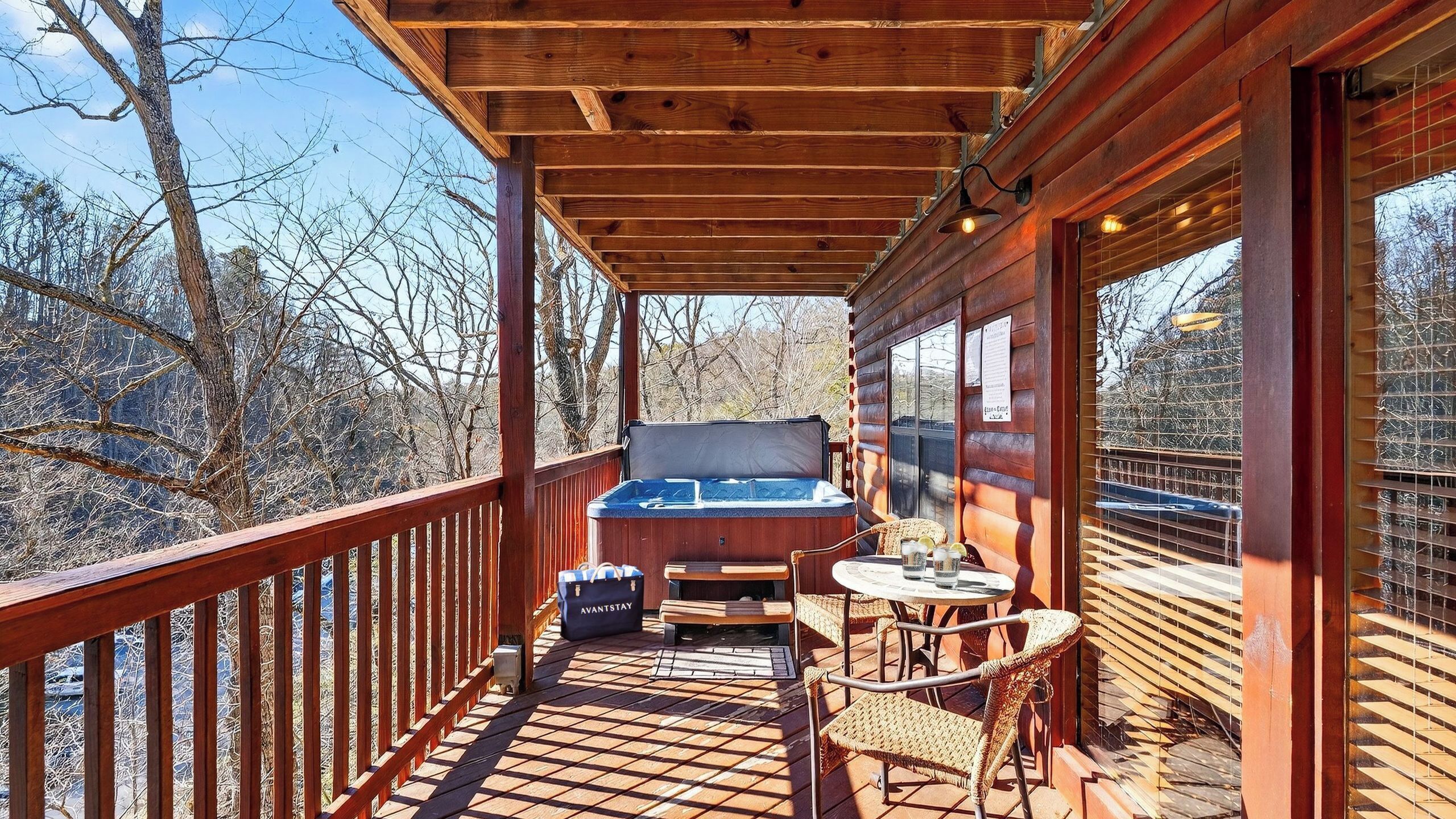 A wooden deck with a hot tub, seating area, and a view of trees.