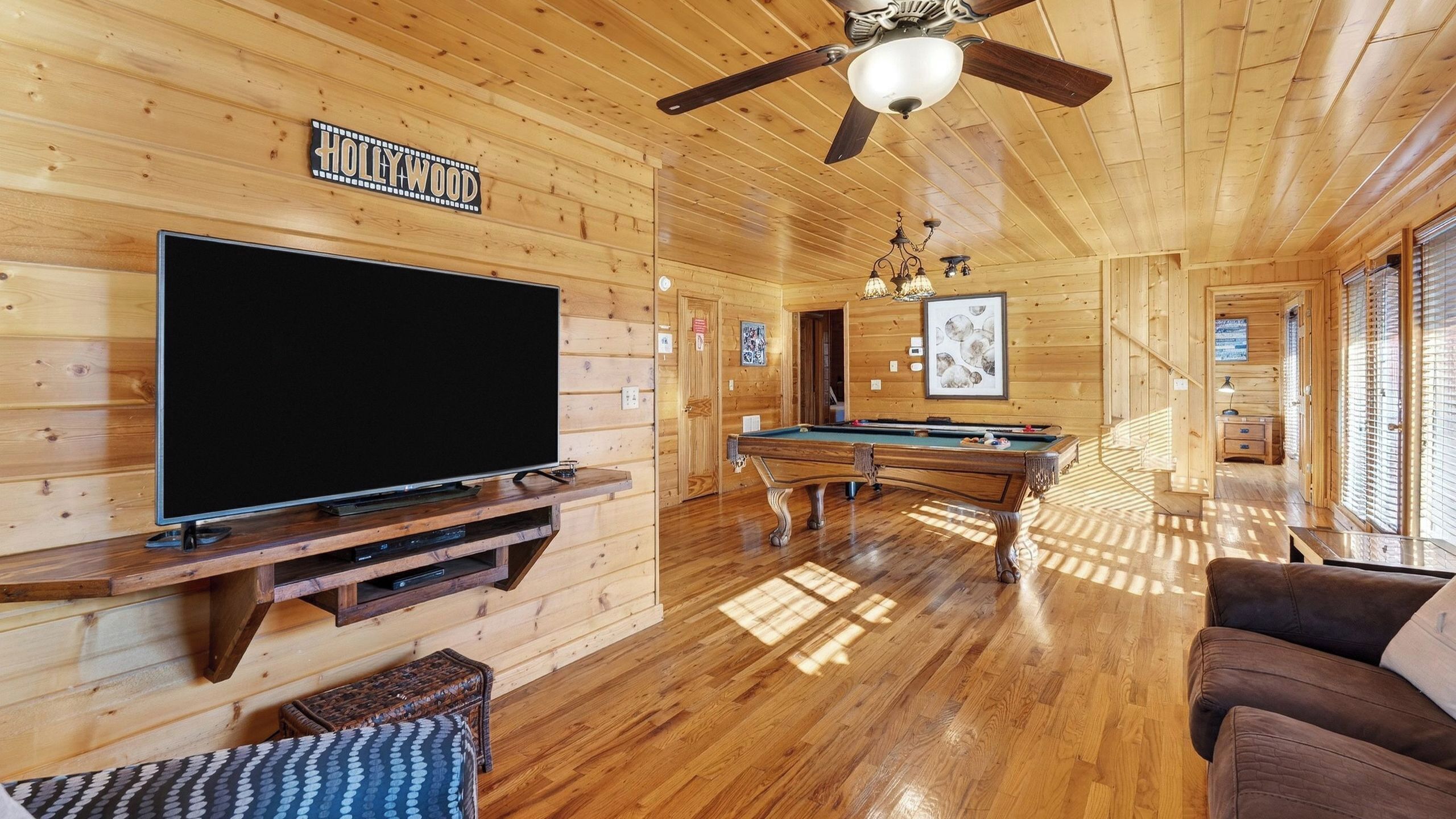 Ein Holzblockhaus-Interieur mit Fernseher, Billardtisch und Deckenventilator.
