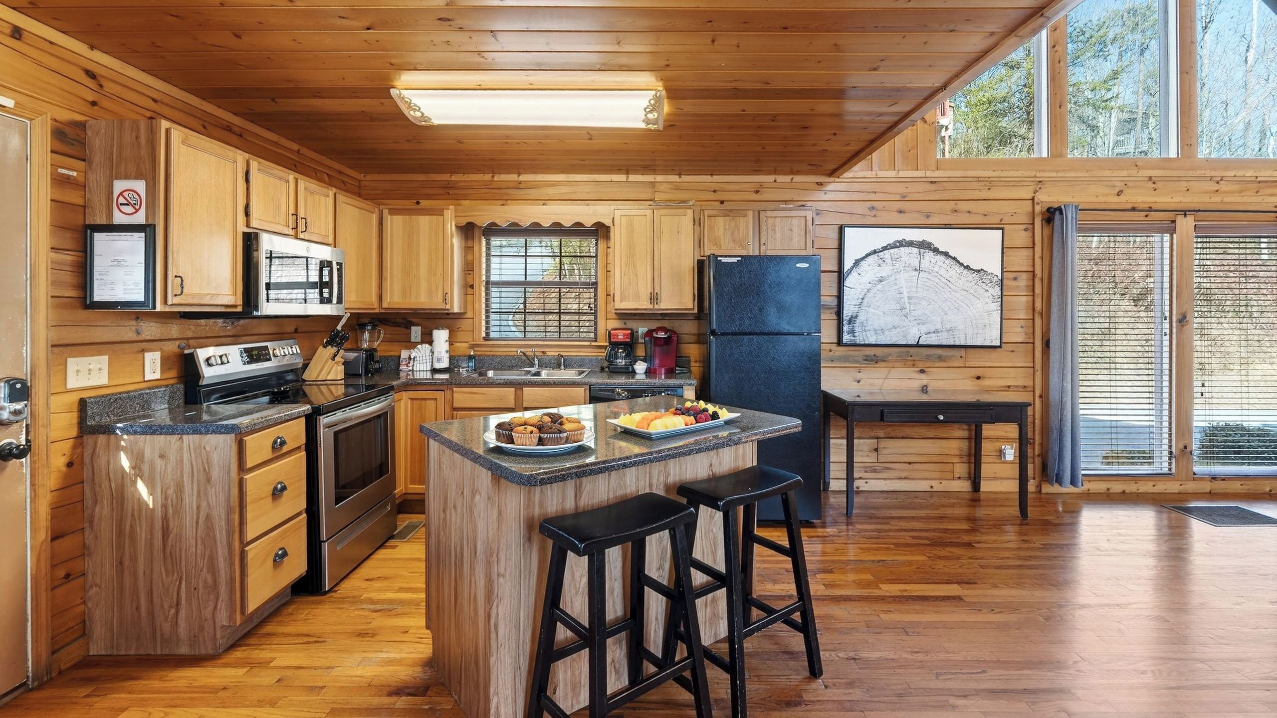 A spacious kitchen with wooden cabinets, a central island with stools, a refrigerator, and a coffee maker.