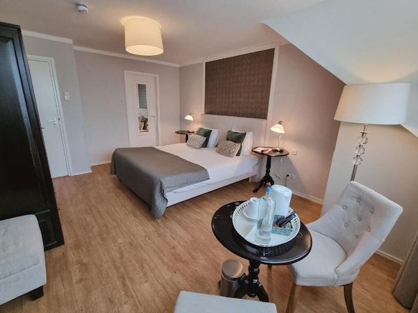 A hotel room with a bed, bedside tables, a chair, a small table with a tray, and a lamp. - Hotel Brull by Beautique Hotels (Mechelen)