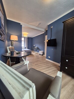 A modern living room with a round glass table, a sofa, a TV mounted on the wall, and a large cabinet.