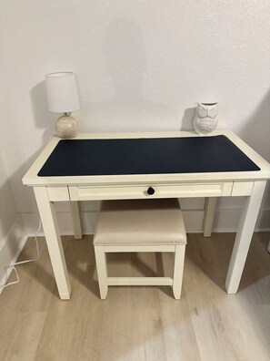 A white desk with a black felt top, a small bench, a lamp, and a ceramic owl on a white wall. - New Listing: perfect location, Sunshine Cottage,  a cute little gem in Lakeside! (Muskegon)