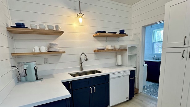 A modern kitchen with white cabinetry, wooden shelves, and a built-in dishwasher. - New Listing: perfect location, Sunshine Cottage,  a cute little gem in Lakeside! (Muskegon)