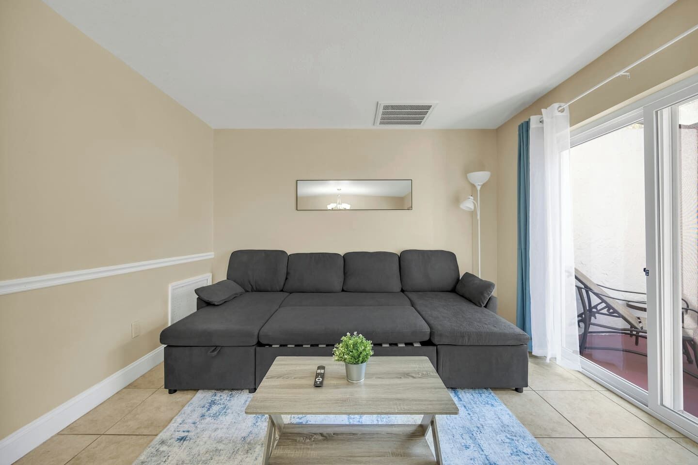 A living room with a dark grey sofa, a wooden coffee table, and a small potted plant.