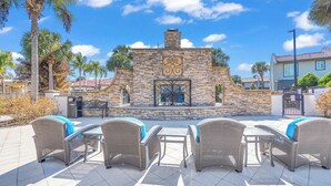 A patio area with wicker furniture and a stone wall with a decorative metal gate. - K-Pop Idol Palace | Disney, River & Slides (Kissimmee)