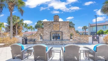 A patio area with wicker furniture and a stone wall with a decorative metal gate.