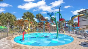 A water park with a central pool, colorful water slides, and palm trees in the background. - K-Pop Idol Palace | Disney, River & Slides (Kissimmee)