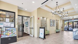A hotel lobby with a reception desk, a glass display case, a seating area, and a sign for the resort activities center. - K-Pop Idol Palace | Disney, River & Slides (Kissimmee)