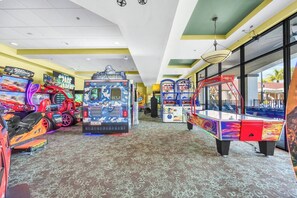 Ein Spielhallenambiente mit verschiedenen Automaten, darunter Renn- und Basketballspiele, in einem hell erleuchteten Innenbereich.