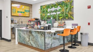 A modern cafe with a marble counter, orange chairs, a coffee machine, and a menu board. - Amazing Spider | Disney, Slides & River (Kissimmee)