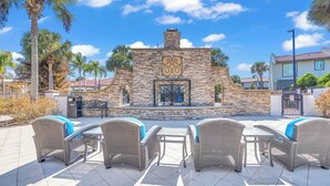 An outdoor patio area with stone walls, a decorative gate, and wicker furniture. - Amazing Spider | Disney, Slides & River (Kissimmee)