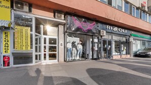 A storefront with a glass entrance, mannequins displaying clothing, and a sign for 'RIZOLI'. - Cozy 2-bedroom apartment in beautiful București with AC (București)